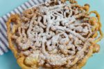 Funnel cake with powdered sugar on blue background
